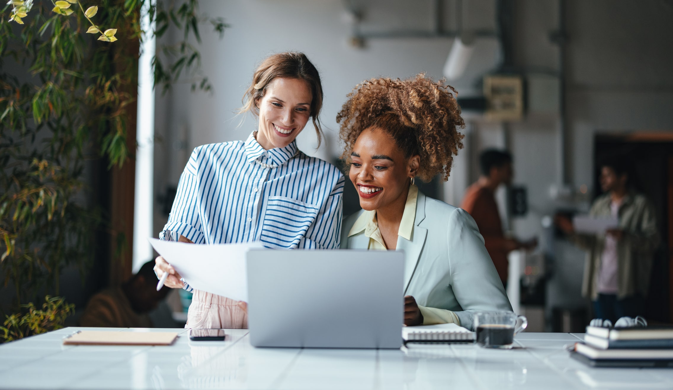 Zwei Frauen lächeln vor einem Computer, während sie kommunizieren
